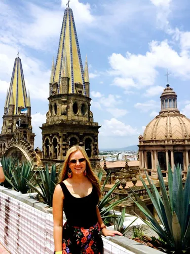 Student standing at a viewpoint with cathedral towers and city skyline in the background.