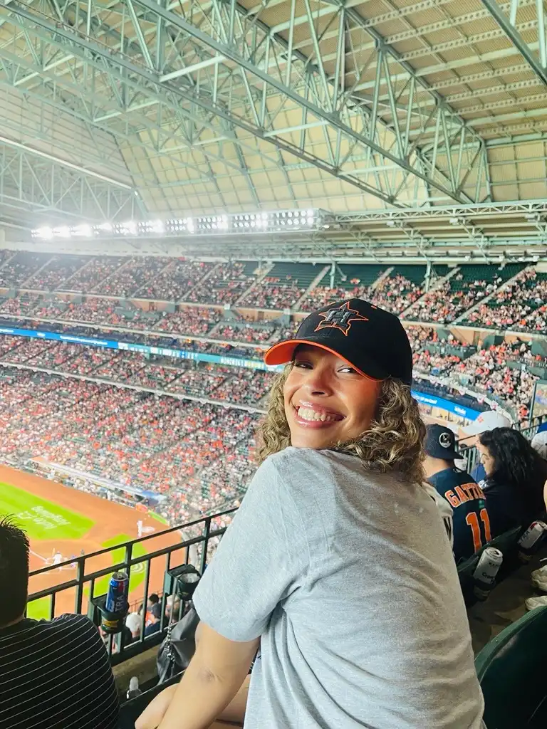 Student smiling in stadium seating during a live sports event