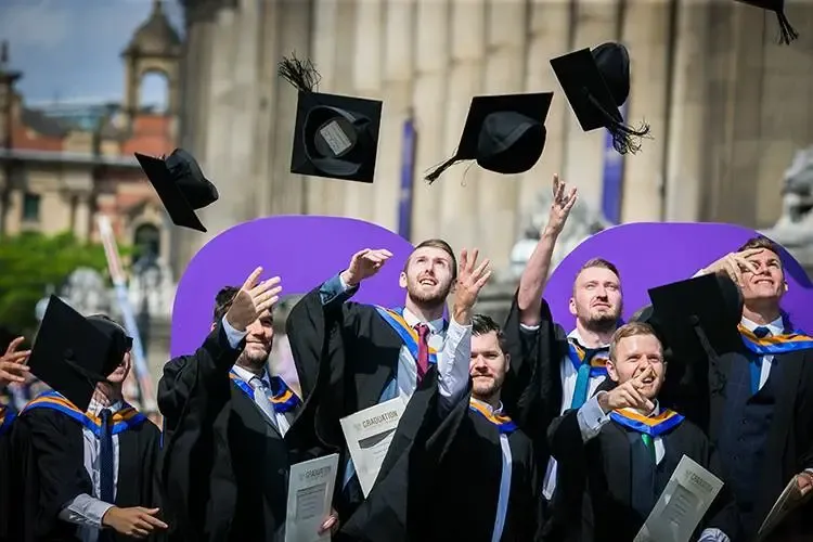 Studenter kaster graduation caps i luften under avslutningsseremoni.