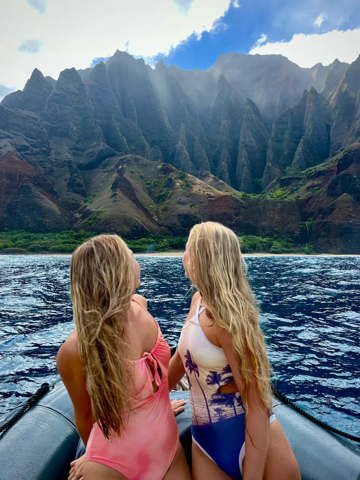 To studenter i båt ser mot bratte fjell og kystlandskap på Hawaii under studier i utlandet