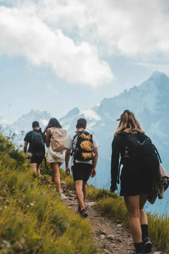 En gruppe elever går langs en fjellsti med ryggsekker og opplever naturen gjennom en lærerik utendørs aktivitet.